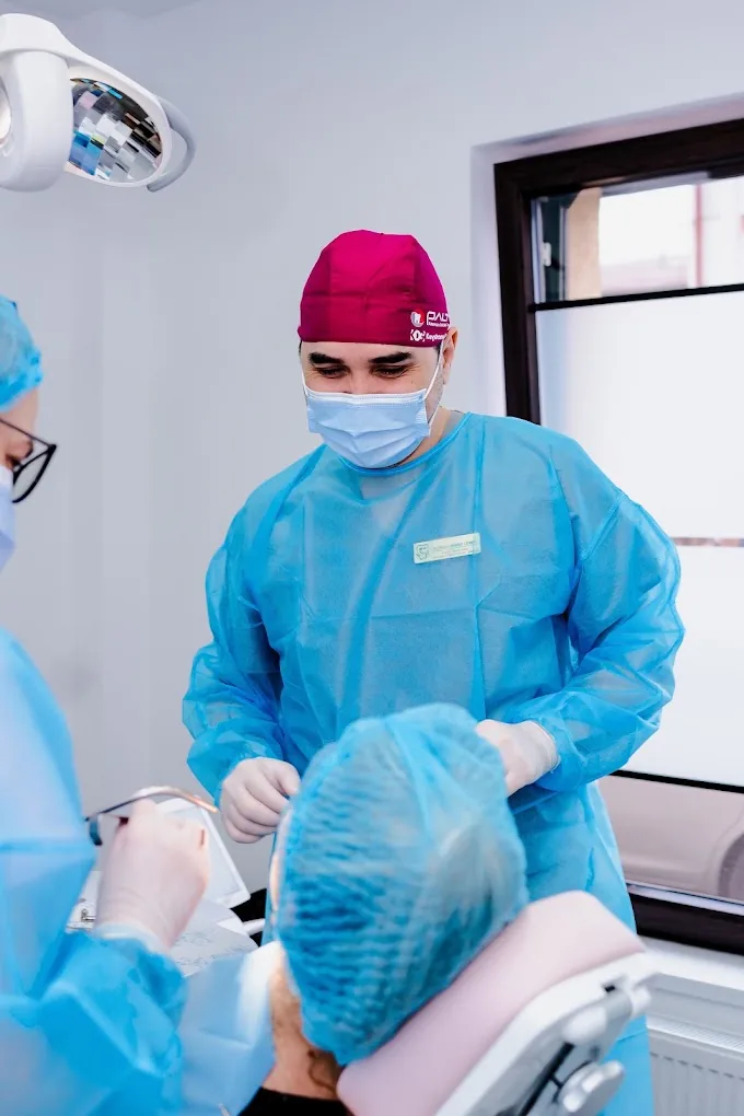 Medic stomatolog pregătind o intervenție, alături de asistentă